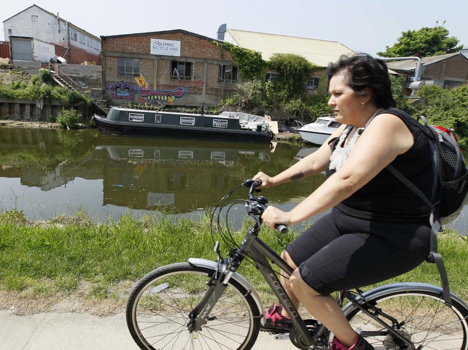 A cyclist passes a cycle hire centre on a canal side cycle path in London, Thursday, May 24, 2012. There are many cycle paths across London that can be used to travel the capital. Like a runner or a swimmer, you would need to be physically fit. Like a goalie or a boxer, you should be prepared for close calls. But if you are coming to London's Summer Olympics _ and you have what it takes _ using a bicycle could be a great option in a city bracing for gridlock. (AP Photo/Kirsty Wigglesworth)