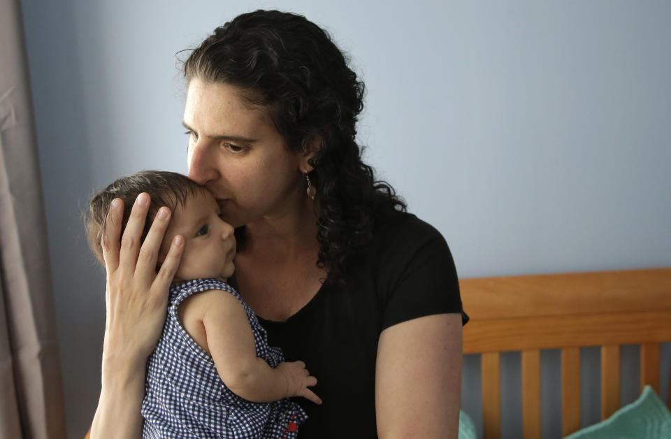 A woman holds her eight-week-old baby in Providence, R.I. After she had her second daughter in April of 2017, she was able to use Rhode Island’s paid family leave program, which started in 2014 and covers four weeks of partial pay. (AP Photo/Steven Senne)