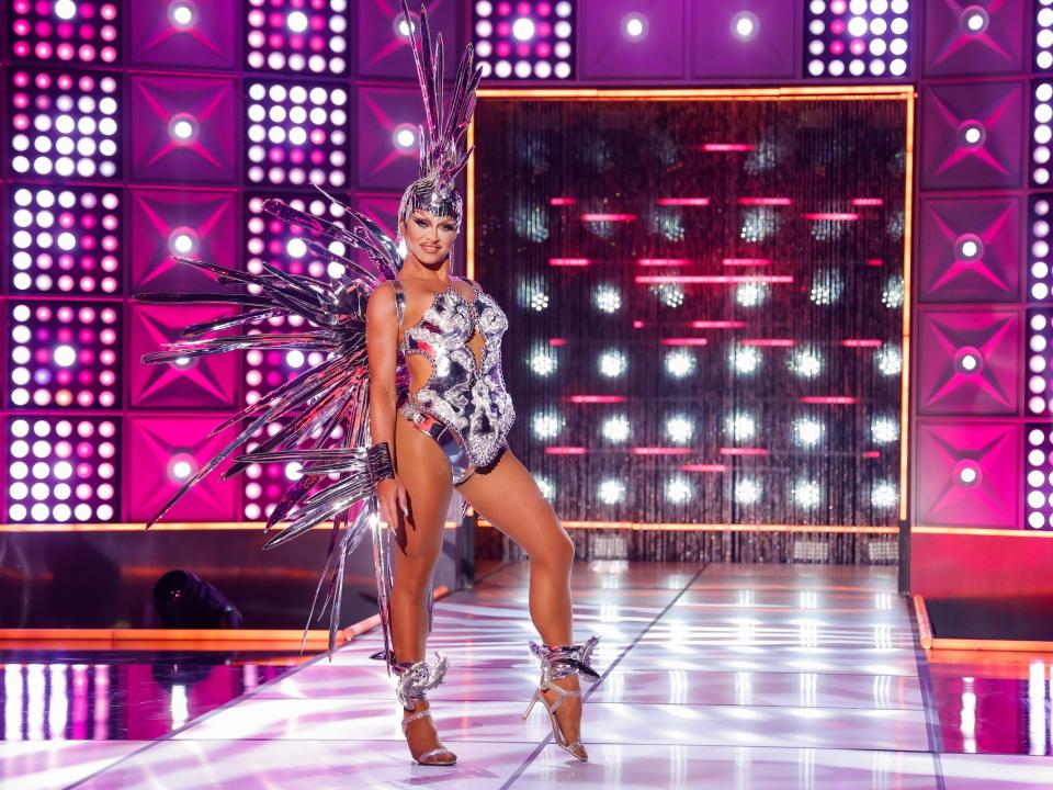 Sasha Colby poses on the runway in a silver bodysuit, silver wings and headdress, and silver heels in this still from episode 3 of "RuPaul's Drag Race" season 15.