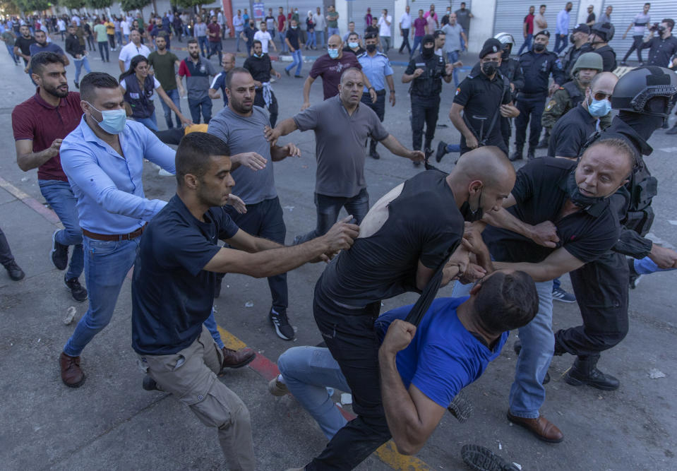 Plainclothes Palestinian security officers detain a protester during clashes that erupted during a demonstration against the death of Nizar Banat, a critic of the Palestinian Authority, in the West Bank city of Ramallah, Saturday, June 26, 2021. Nearly two weeks after he was severely beaten by Palestinian security forces, Akil Awawdeh is still short of breath, still shielding his bruised chest with his hand and still haunted by the screams inside the police station. (AP Photo/Nasser Nasser)