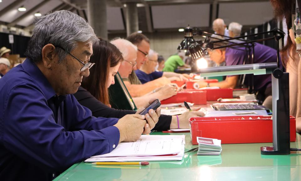 A collector checks his smartphone for stamps he needs during the Great American Stamp Show last August in Sacramento, California. This year's stamp show is in downtown Cleveland running today through Sunday. Admission is free.