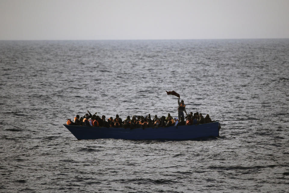 Migrants and refugees wave for help from inside a wooden boat 21 miles north of Sabratha, Libya, on Friday, Feb. 3, 2017. European Union leaders are poised to take a big step on Friday in closing off the illegal migration route from Libya across the central Mediterranean, where thousands have died trying to reach the EU, the EU chief said. (AP Photo/Emilio Morenatti)