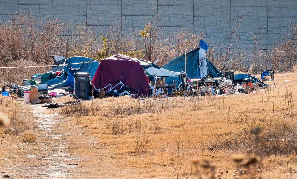 Homeless camps are pictured Dec. 11 in a field at the southeast corner of NW 5 and Western Avenue in Oklahoma City. The wall is the westbound Interstate 40 retaining wall.