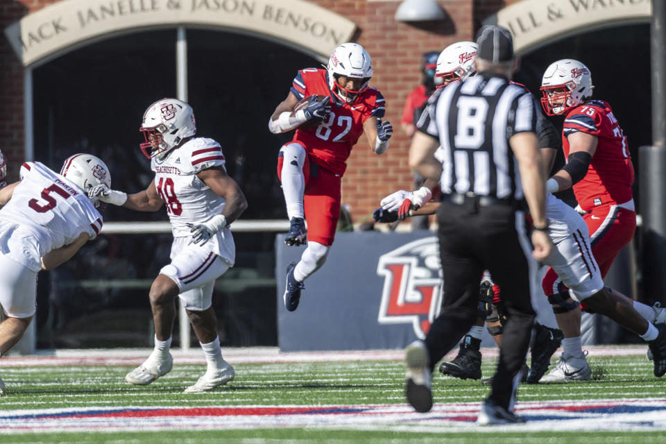 Liberty's Aaron Bedgood (82) runs for a first down defended by UMass' Jerry Roberts Jr. and Tyler Martin during the first half of an NCAA college football game, Saturday, Nov. 18, 2023, in Lynchburg, Va. (AP Photo/Robert Simmons)