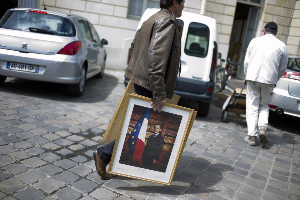 FILE - In this May 15, 2012 file photo a worker removes the official portraits of former French President Nicolas Sarkozy, at Elysee Palace. The trial of former French President Nicolas Sarkozy concludes Tuesday in Paris, after a month during which the court sought to determine whether he broke laws on campaign financing in his unsuccessful 2012 re-election bid. (AP Photo/Thibault Camus, File)