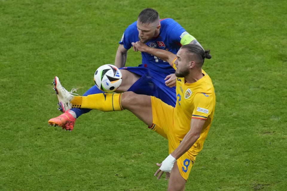 Geroge Puscas, de la selección de Rumania, disputa una pelota con Milan Skriniar, de Eslovaquia, durante el encuentro de la Eurocopa disputado el miércoles 26 de junio de 2024, en Fráncfort (AP Foto/Darko Vojinovic)