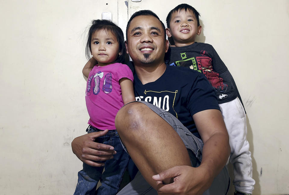 In this May 4, 2018 photo, Vanna In, center, poses for photos with two of his three children, Thanny, left, and Jeevin in Fresno, Calif. California Gov. Jerry Brown announced Friday, Aug. 17, 2018, he pardoned three former prisoners facing the threat of deportation to Cambodia, including Vanna In, who became a youth pastor after serving six years in the 1990s for murdering a rival gang member. (Eric Paul Zamora/The Fresno Bee via AP)