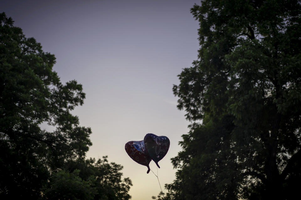 Two heart balloons are silhouetted against the dusk sky at a memorial site for victims of the mass shooting at Robb Elementary School in the town square of Uvalde, Texas, Friday, May 27, 2022. (AP Photo/Wong Maye-E)