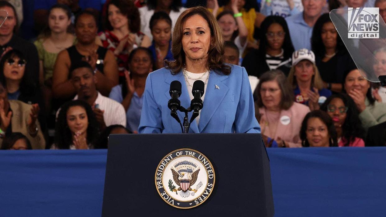 Vice President Kamala Harris in a blue suit stands at the podium