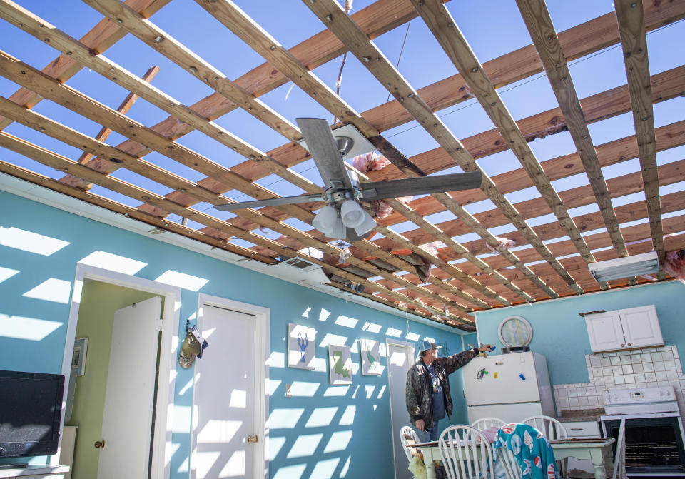 Randall Bordelon, far right, looks around the kitchen in his fishing camp near Chauvin, La., on Thursday, Oct. 29, 2020 after Hurricane Zeta destroyed the roof. Gov. John Bel Edwards says officials are still assessing the extent of Zeta’s damage across the southeastern parishes. (Chris Granger/The Advocate via AP)