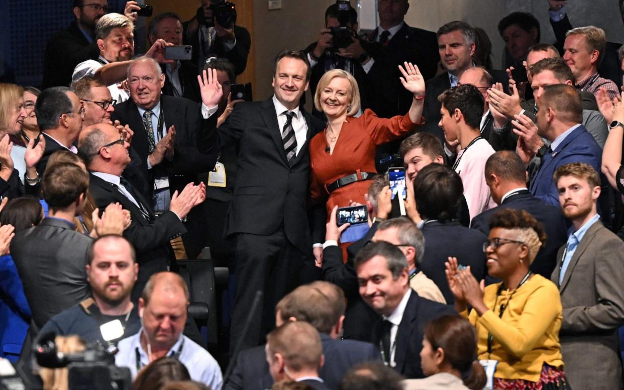 Liz Truss and her husband Hugh O'Leary wave to delegates at the Conservative Party Conference - OLI SCARFF/AFP