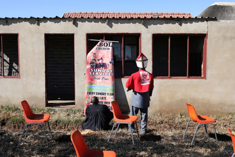 Tsietsi Makiti, a self-styled "Pope" of Gabula Church, looks on as his congregant helps to put up a banner in Evaton