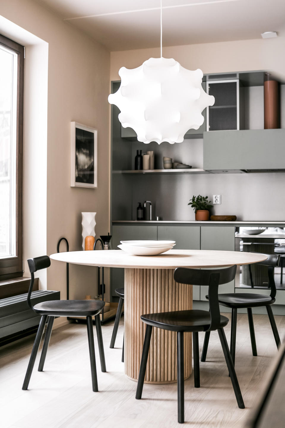 A dining room with pink walls and grey cabinets