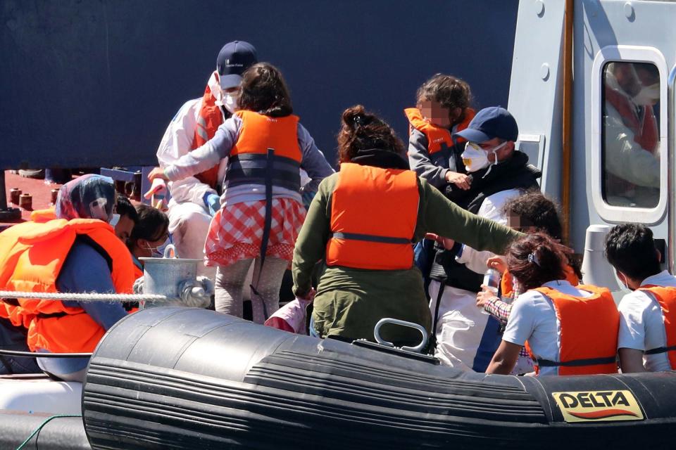 A Border Force officer escorts a young family thought to be migrants from a Border Force vessel (PA)