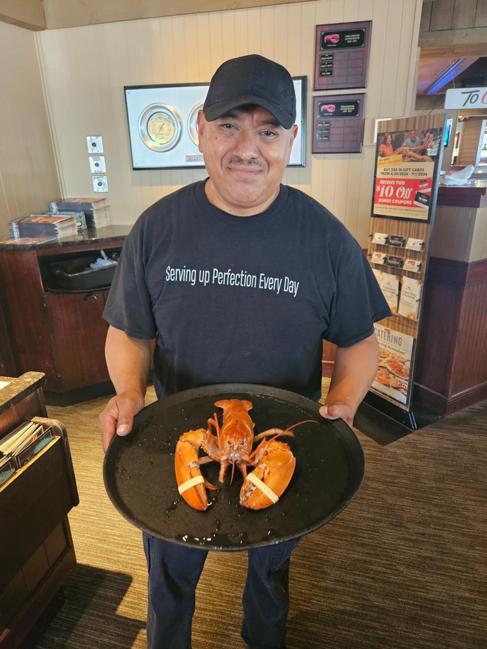 Jose Romero holds up a rare orange lobster named Crush, which Romero found in a shipment of live lobsters sent to the Pueblo Red Lobster on July 12.