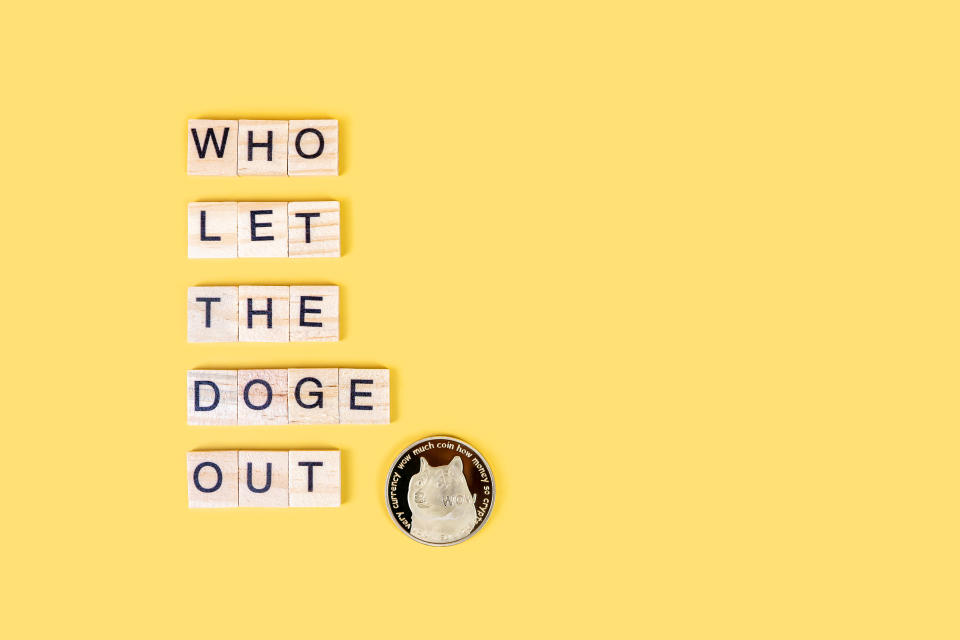 Who let the Doge out, funny sign about Dogecoin crypto with wooden blocks and coin with dog&#39;s face isolated on yellow background. Creative banner with copy space