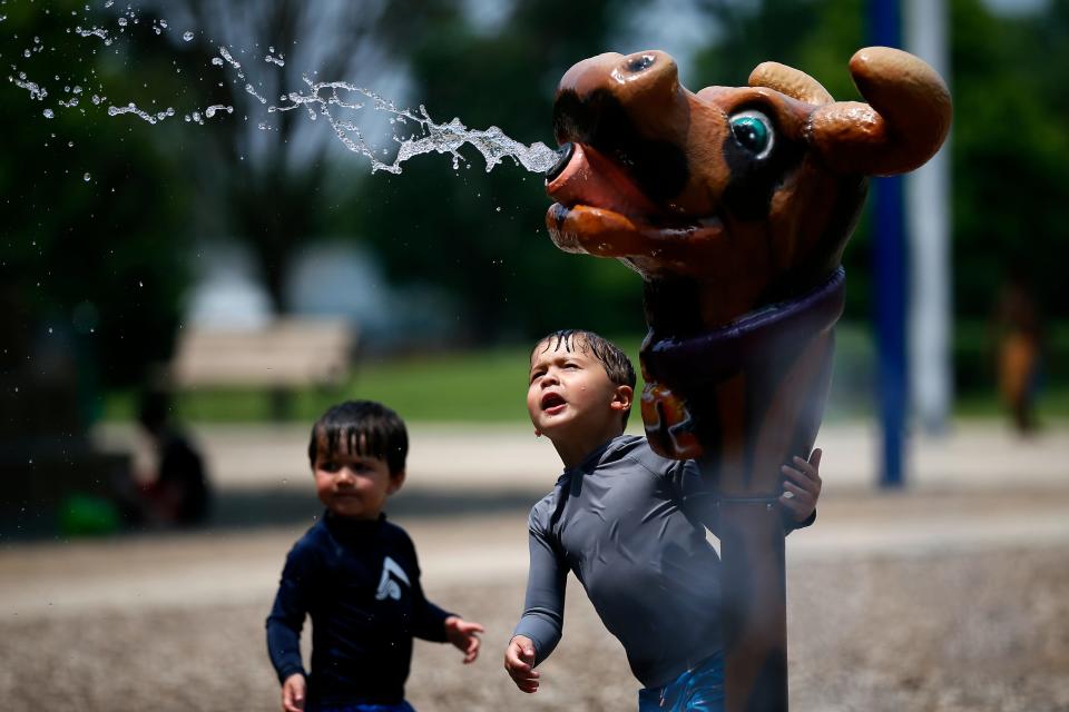 Sterling DeCilles, 4, (right) directs a spray nozzle for his little brother, Judah, 2, on the splash pad at Juilfs Park in Anderson Township, Ohio, on Monday, June 13, 2022.