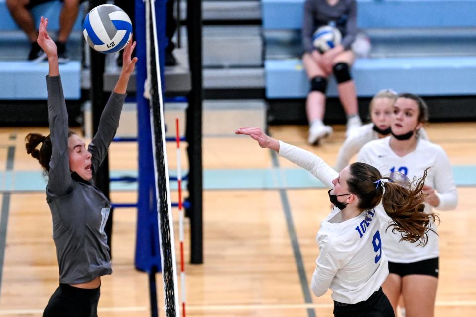 Ionia's Tess Griffith, right, spikes the ball as Lansing Catholic's Nina Hufnagel defends during the first set on Monday, Sept. 20, 2021, at Lansing Catholic High School. 