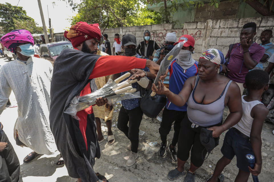 Nertil Marcelin, leader of a community group, distributes machetes to residents in an initiative to resist gangs seeking to take control of their neighborhood, in the Delmas district of Port-au-Prince, Haiti, Saturday, May 13, 2023. (AP Photo/Odelyn Joseph)