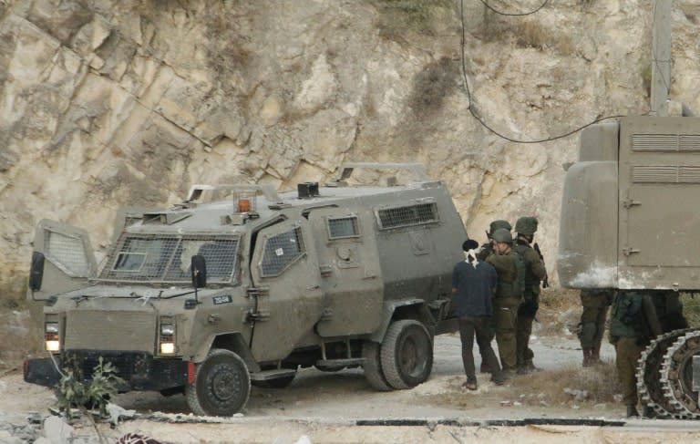 Israeli soldiers arrest a man during a raid in Surif, north of the West Bank city of Hebron to search for a Hamas militant accused of murdering an Israeli rabbi