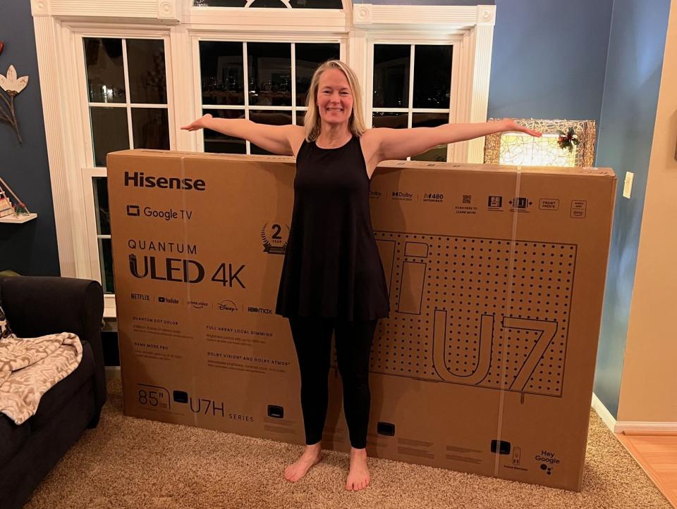 My wife standing in front of the Hisense U7H box. She's not a small person; the TV is simply huge.