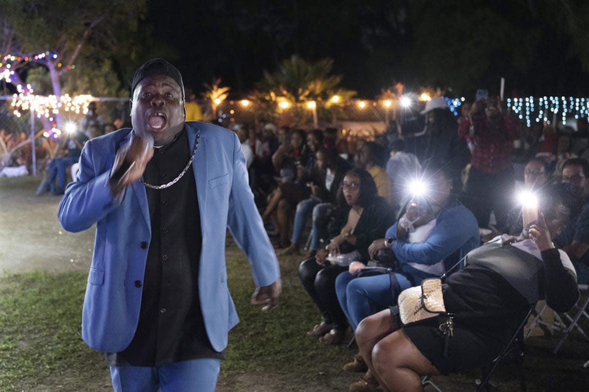 Bishop Lawrence Rolle performs in front of children and adults at Mt. Carmel Preparatory Academy in Nassau, Bahamas on Thursday, Dec. 8, 2022. Rolle’s ministry received $50,000 from FTX in early 2022, one of several donations the cryptocurrency exchange made to the Bahamian people when it relocated to the Caribbean island nation in 2021. (AP Photo/Ken Sweet)