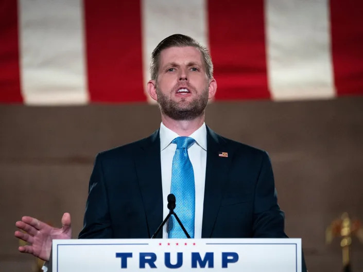 Eric Trump stands at a podium.