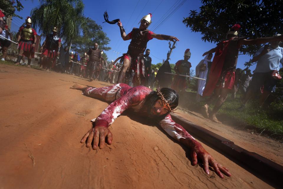 An actor, playing the role of Jesus Christ, is whipped by a Roman soldier as he falls during a Way of the Cross reenactment, as part of Holy Week celebrations, in Atyra, Paraguay, Friday, March 29, 2024. Holy Week commemorates the last week of Jesus' earthly life which culminates with his crucifixion on Good Friday and his resurrection on Easter Sunday. (AP Photo/Jorge Saenz)