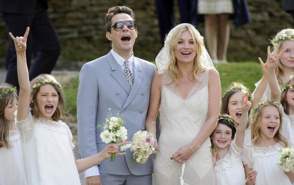 FILE - In this July 1, 2011 file photo, British model Kate Moss and British guitarist Jamie Hince pose for photographers with unidentified bridesmaids, after their wedding in the village of Southrop, England. Brides may want to take a page from the playbook of the supermodel Moss, who asked her friend John Galliano to make her a vintage style wedding dress, and the designer used Zelda Fitzgerald as inspiration. The cream-colored, bias cut gown featured an Art Deco motif along the bottom, and was embroidered with gold, spangled with gold paillettes. (AP Photo/Jonathan Short, file)