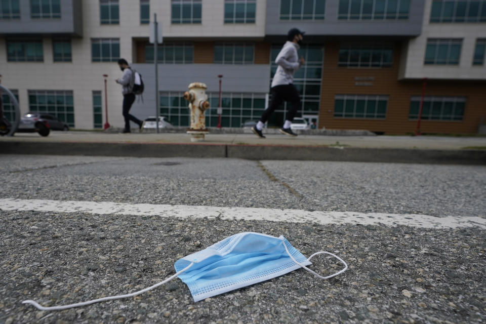 A discarded face mask lies in the street in San Francisco, Wednesday, March 17, 2021. Disposable masks, gloves and other personal protective equipment have safeguarded untold lives during the pandemic. They’re also creating a worldwide environmental problem, littering streets and sending an influx of harmful plastic into landfills and oceans. (AP Photo/Jeff Chiu)