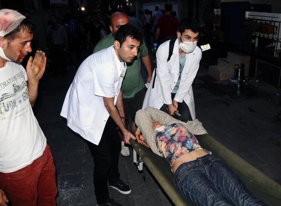 FILE - In this May 31, 2013, file photo, volunteer Turkish doctors help a demonstrator afftected with pepper gas during clashes with riot police near Taksim Square in Istanbul, Turkey. During the height of Turkey's summer of upheaval, more than a dozen Turkish doctors interviewed by The Associated Press say authorities assaulted them with tear gas, pressured them to reveal the names of patients and ignored calls for resources. (AP Photo/Emrah Gurel, File)