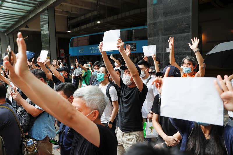 Supporters raise white paper to avoid slogans banned under the national security law as they support arrested anti-law protester outside Eastern court in Hong Kong