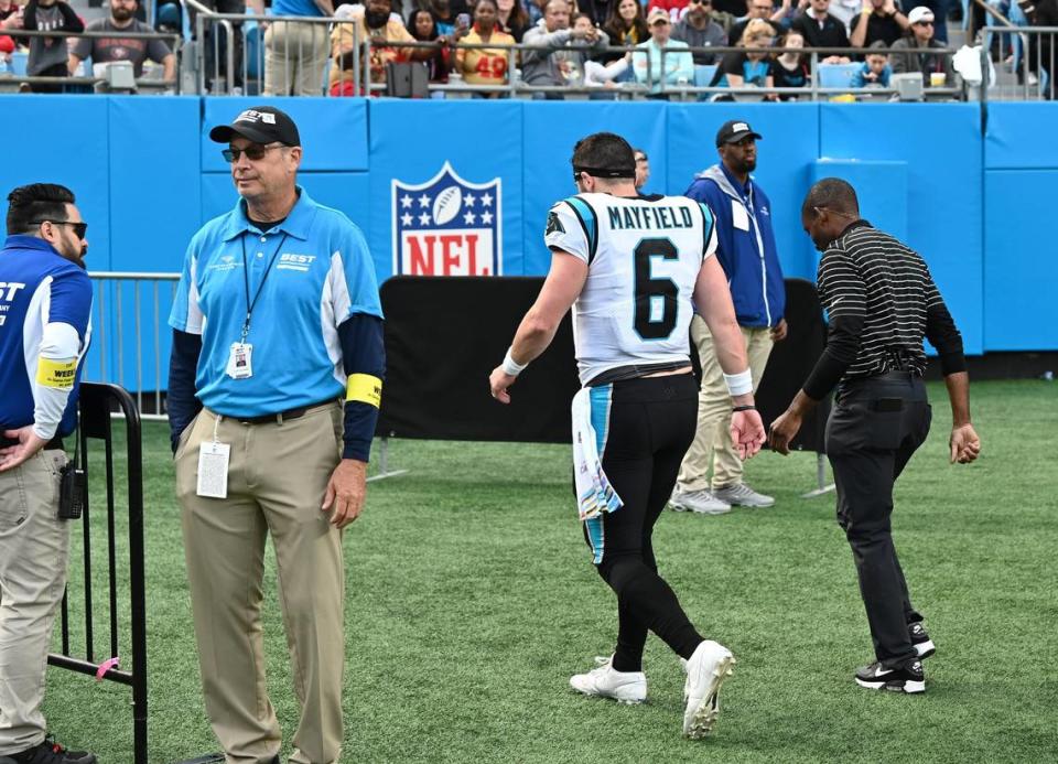 Carolina Panthers quarterback Baker Mayfield, center, walks off the field with the head trainer Kevin King, right, near the end of firs half action against the San Francisco 49ers at Bank of America Stadium on Sunday, October 9, 2022.