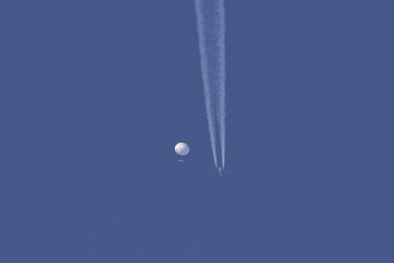 In this photo provided by Brian Branch, a large balloon drifts above the Kingstown, N.C. area, with an airplane and its contrail seen below it. (Brian Branch via AP)