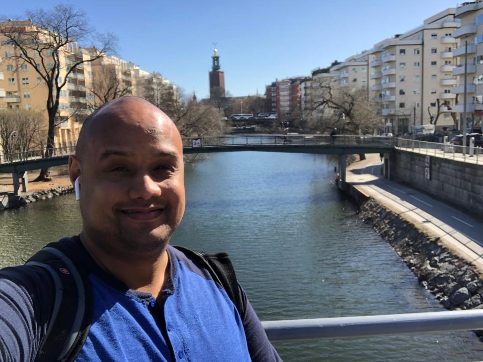 A man taking selfie in front of a river in Europe.