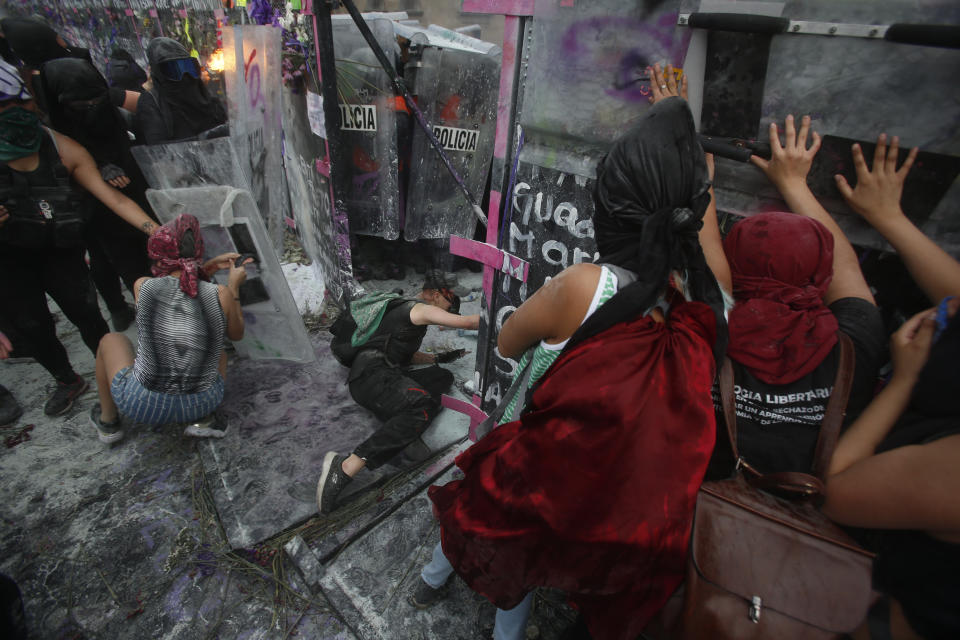 Demonstrators open a breach on a police shield wall at a barricade protecting the National Palace during a march to commemorate International Women's Day and protest against gender violence, in Mexico City, Monday, March 8, 2021. (AP Photo/Ginnette Riquelme)