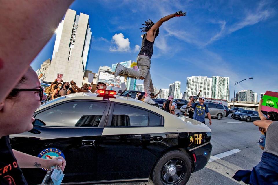 Demonstrators block I-95 and jump on a Florida Highway Patrol car during George Floyd protest in downtown Miami on Saturday, May 30, 2020.