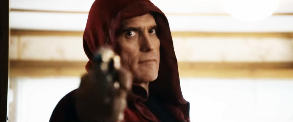 A man wearing a hoodie and holding a gun pointed at the camera