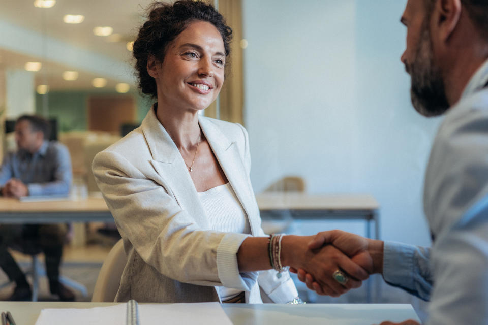 Business people shaking hands in the office. Two entrepreneurs on meeting in board room. HR manager  meet and greet new employee on job interview. Cheerful Businessman and businesswoman greeting each other for successful partnership. Signing new agreement in modern office