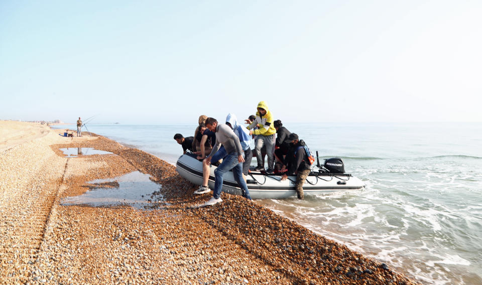 An angler watches as a group of people thought to be migrants arrive in an inflatable boat at Kingsdown beach, near Dover, Kent, after crossing the English Channel.