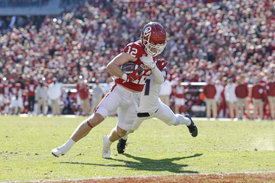 Oklahoma wide receiver Drake Stoops (12) drags TCU safety Abe Camara (1) into the end zone for a touchdown during the second half of an NCAA college football game Friday, Nov. 24, 2023, in Norman, Okla. Oklahoma won 69-45. (AP Photo/Alonzo Adams)