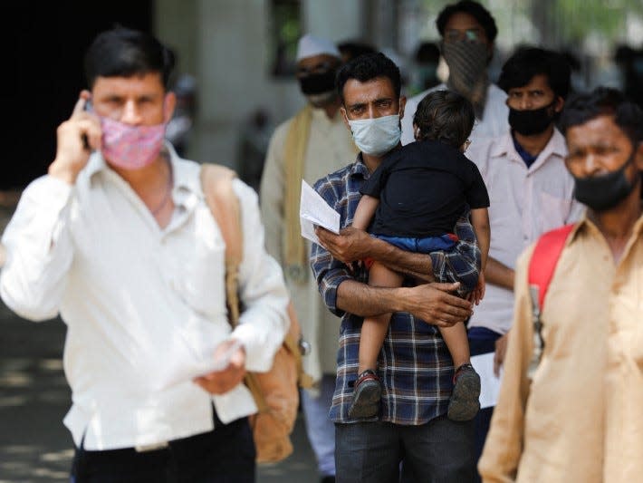 A man carries his son as he stands with others in a queue at a Railway reservation ticket counter after a few restrictions were lifted during an extended nationwide lockdown to slow the spread of the coronavirus disease (COVID-19), in New Delhi, India, June 1, 2020. REUTERS/Adnan Abidi