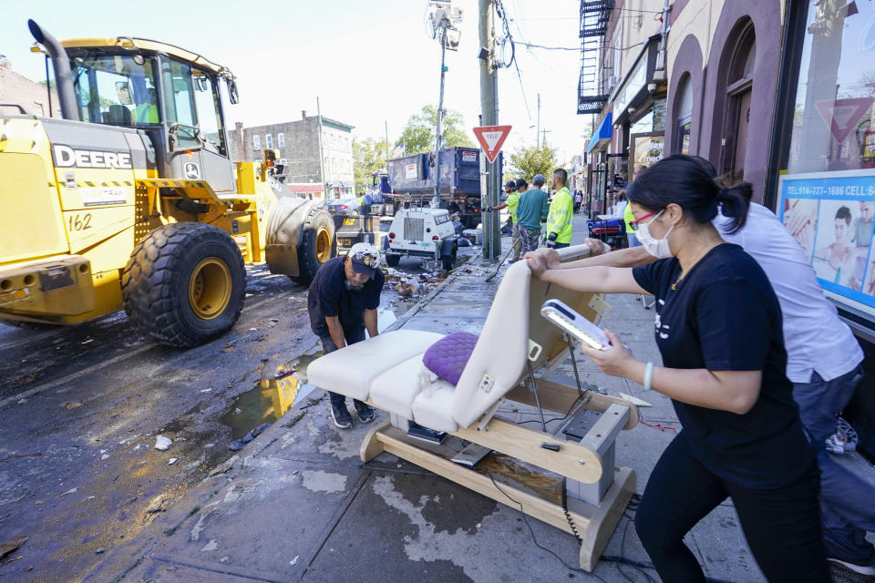 Business owner put out water logged equipment as Village of Mamaroneck workers use a front loader to remove water logged items from the sidewalk after remnants of Hurricane Ida inundated the community, Saturday, Sept. 4, 2021, in Mamaroneck, N.Y. More than four days after the hurricane blew ashore in Louisiana, Ida's rainy remains hit the Northeast with stunning fury on Wednesday and Thursday, submerging cars, swamping subway stations and basement apartments and drowning scores of people in five states. (AP Photo/Mary Altaffer)