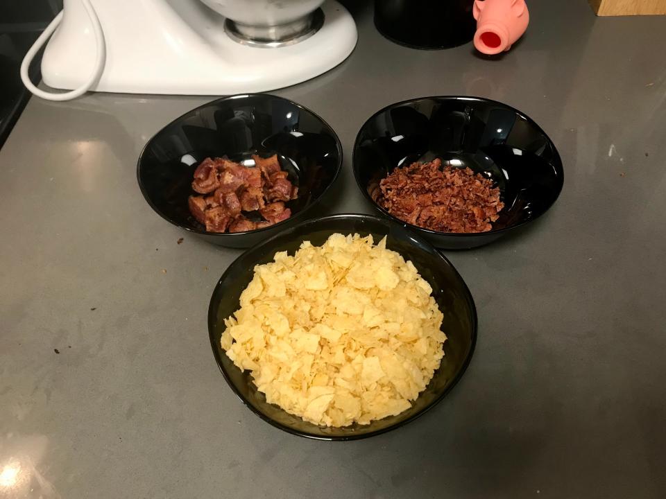 Crushed potato chips and chopped bacon sitting in three black bowls in preparation of Martha Stewart's Bacon Potato-Chip Chocolate Cookie recipe.