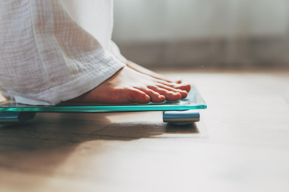 Maintaining a calorie deficit for an extended period can have adverse effects. (Getty) Female feet standing on electronic scales for weight control on wooden background. The concept of slimming and weight loss