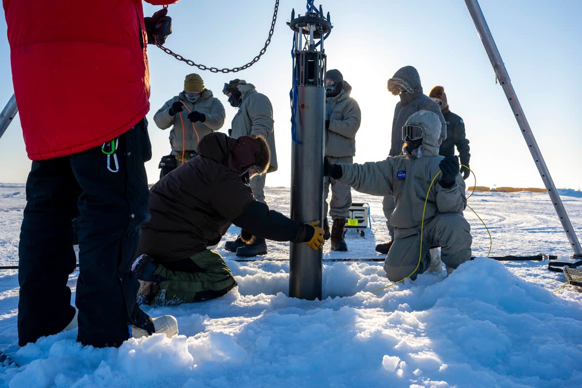 Nasa researchers work on a field test of the autonomous IceNode robot north of Alaska in March. Scientists at the agency’s  Jet Propulsion Laboratory are hoping to develop a fleet of these robots some day, to help better understand ice shelf melt rates.   (U.S. Navy/Scott Barnes)