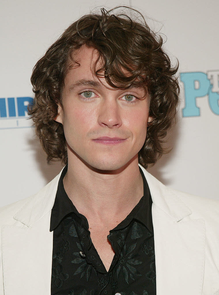 with long curly hair and clean face wearing a blazer