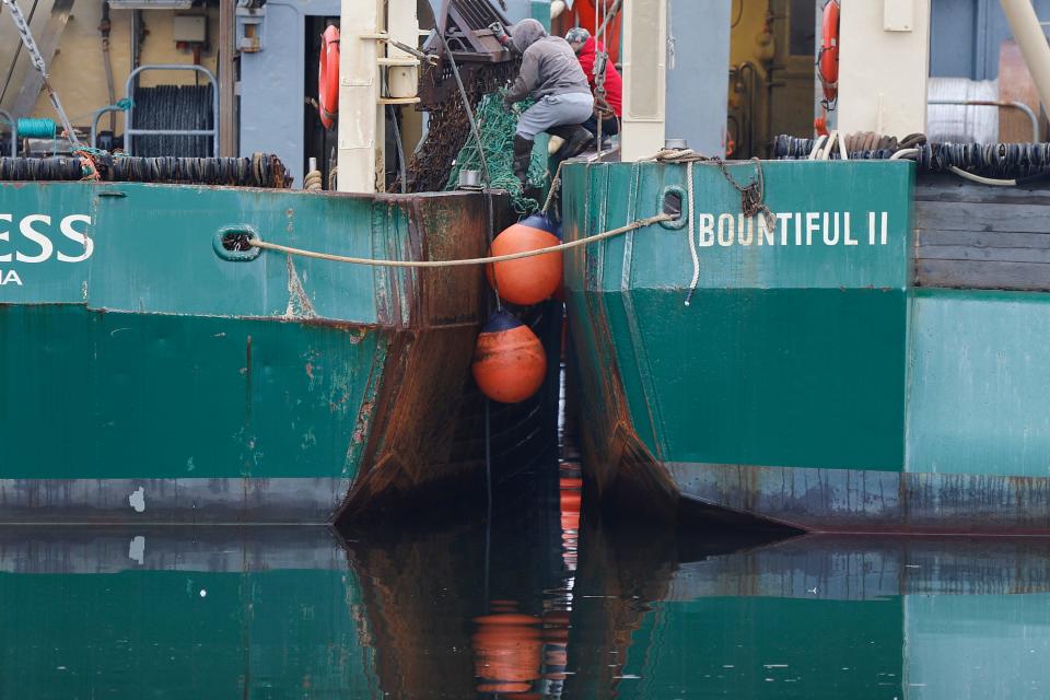 Fishermen fix the dredge netting from the scalloper Huntress while balancing between boats in Fairhaven.