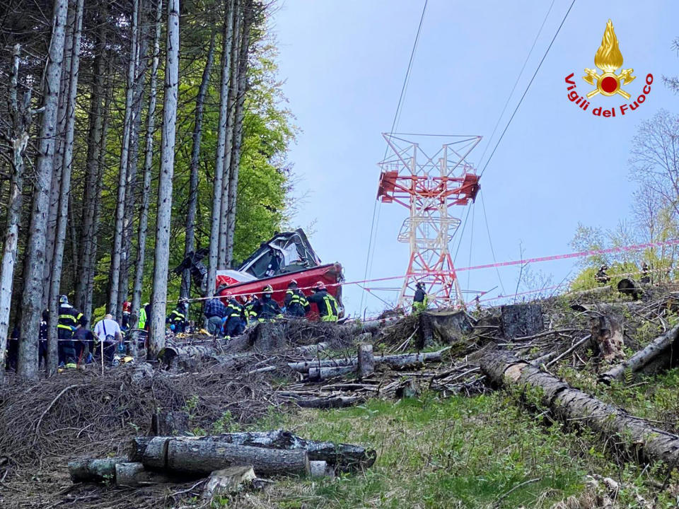 Rescuers work by the wreckage of a cable car after it collapsed near the summit of the Stresa-Mottarone line in the Piedmont region, northern Italy, Sunday, May 23, 2021. A cable car taking visitors to a mountaintop view of some of northern Italy's most picturesque lakes plunged to the ground Sunday, killing at least nine people and sending two children to the hospital, authorities said. (Italian Vigili del Fuoco Firefighters via AP)