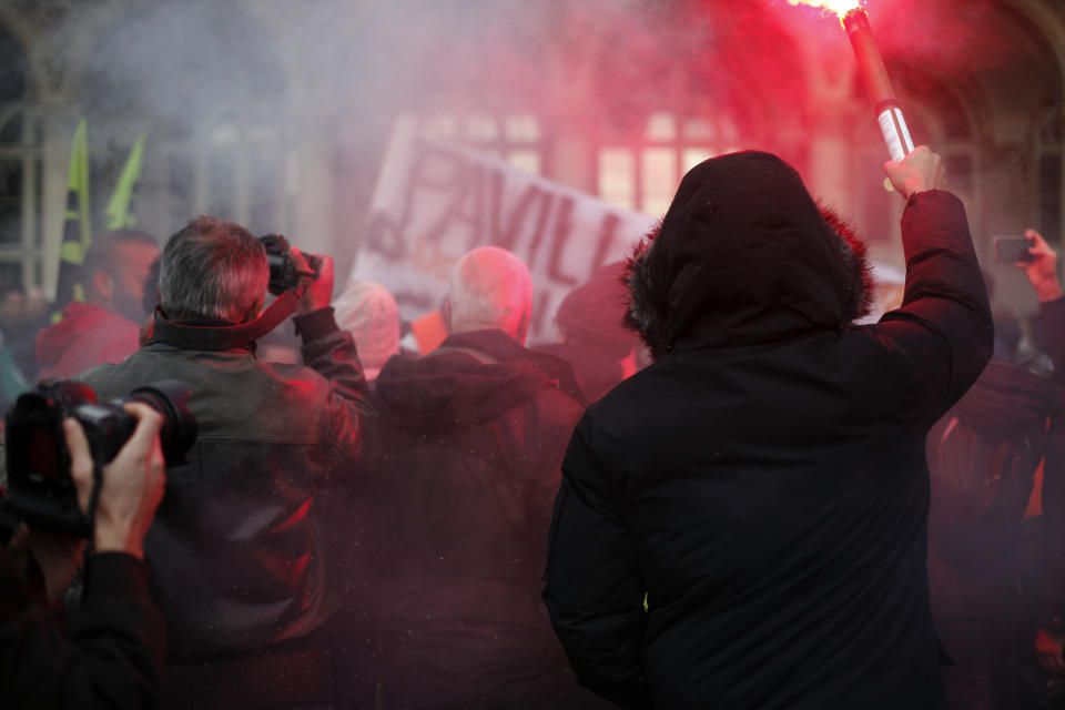 A protestor holds a flare as he demonstrates after 22 days on a strike against pension reform plans, in Paris, Thursday, Dec. 26, 2019. France's punishing transportation troubles may ease up slightly over Christmas, but unions plan renewed strikes and protests in January to resist government plans to raise the retirement age to 64. (AP Photo/Thibault Camus)